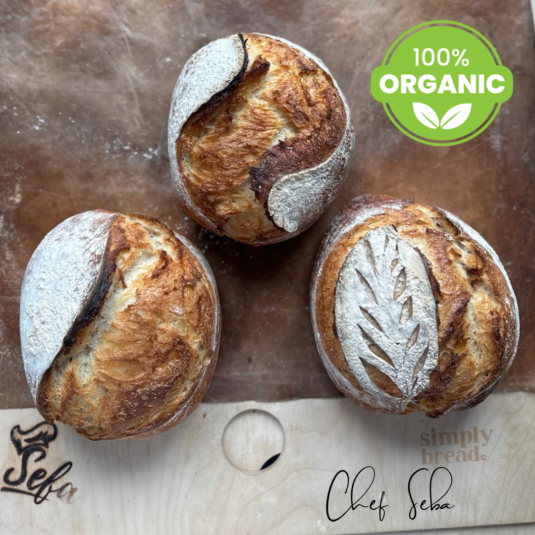 Three organic bread loaves on a wooden board with 'Real Artisan 100% Organic SOURDOUGH ' label and 'Chef Seba' branding. Super Dupadough bread!