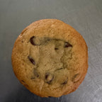 SEBA Artisan Sourdough Chocolate Chip Cookie - Artisan Real Sourdough Bread Chef SebaArtisan Real Sourdough Bread Chef SebaArtisan Real Sourdough Bread Chef SebaSEBA-CCC-120A single chocolate chip muffin with golden-brown baked chips visible on top, photographed from above on a gray metal surface.
