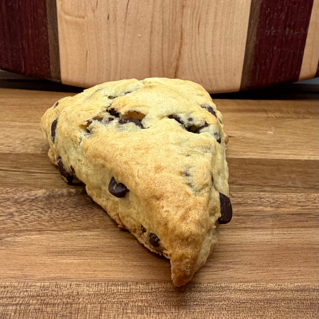 Sourdough Chocolate Chip Scones in Des Plaines, IL | Fresh Artisan Bakery by Chef SEBA - Artisan Real Sourdough Bread Chef SebaArtisan Real Sourdough Bread Chef SebaArtisan Real Sourdough Bread Chef SebaSTRAW-SCONE-01singleSour dough scone with chocolate chips on a wooden surface, branded 'Dempsey & Peabody'.